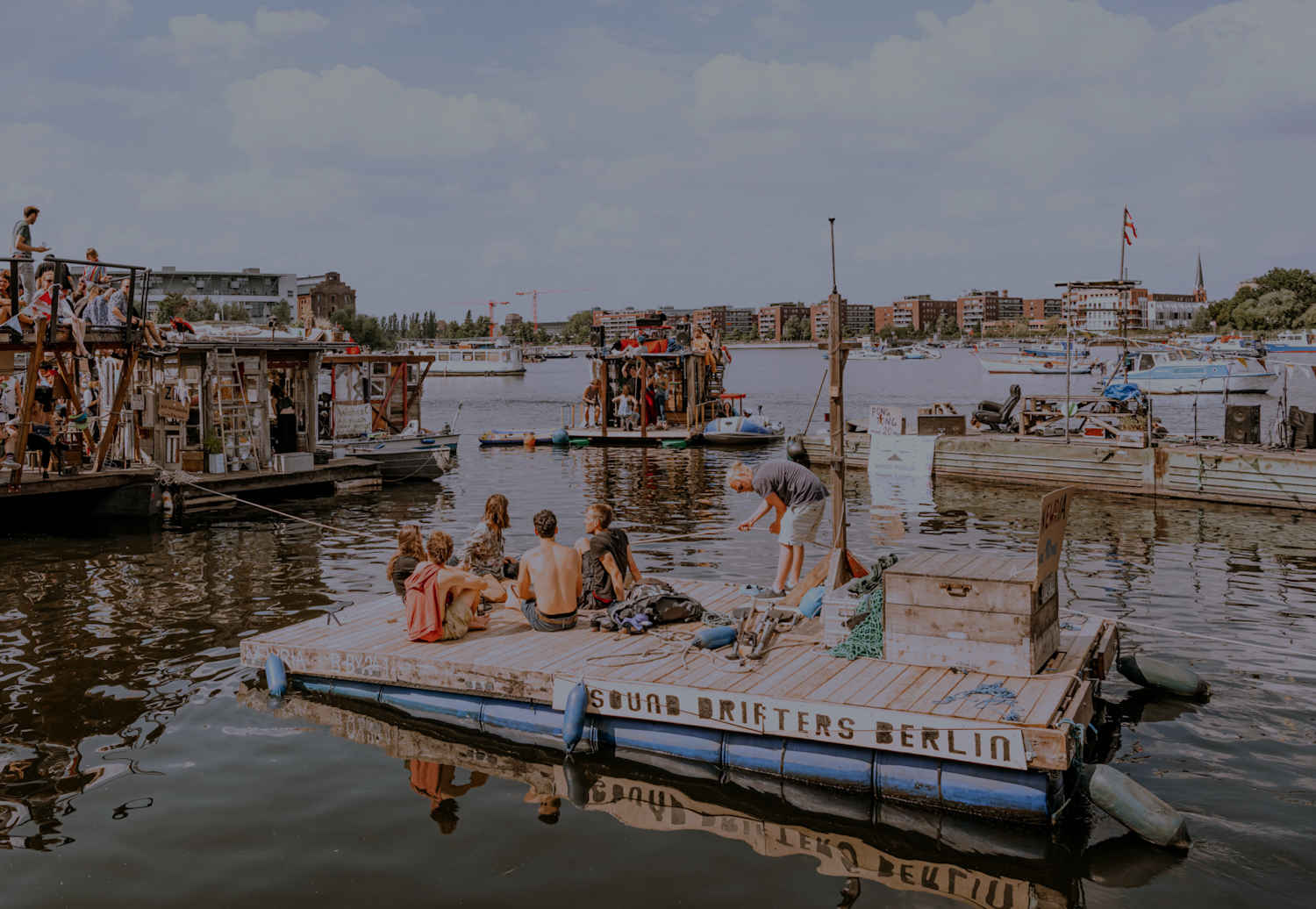 Riva della Sprea al tramonto con magazzini industriali riconvertiti e bar all'aperto