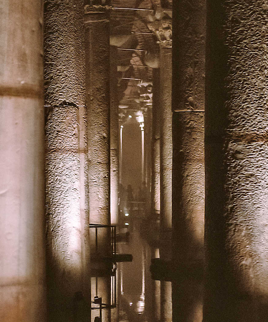 Volta buia di una cisterna sotterranea con riflessi d'acqua e stalattiti di calcare